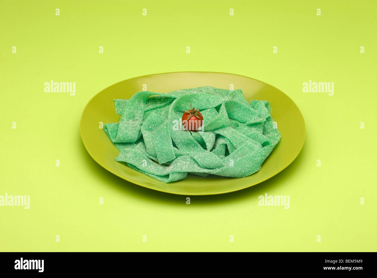 Food-Konzept, Teller mit grünen Gummibärchen Bonbons angeordnet wie Nudeln garniert mit Cherry-Tomaten Stockfoto