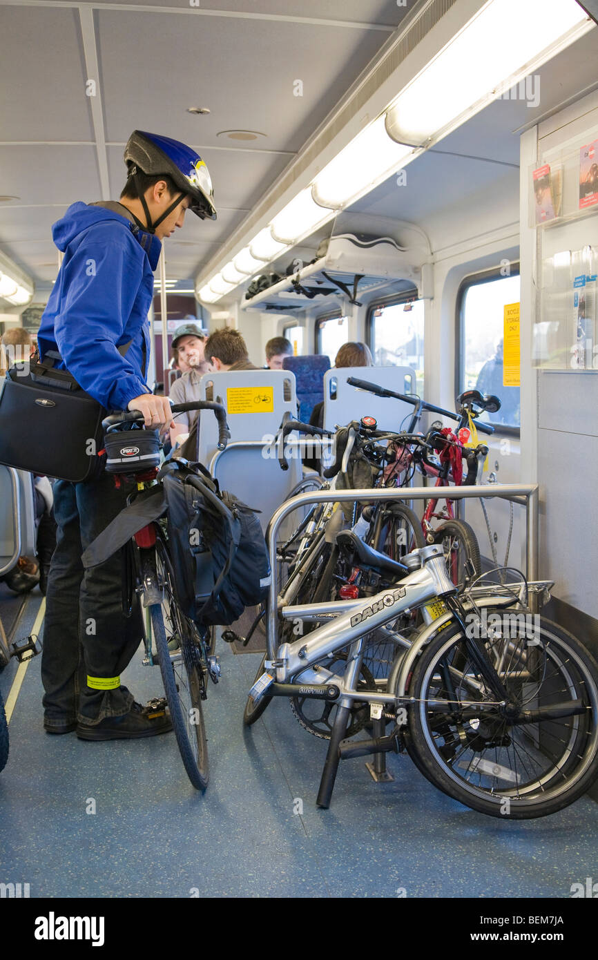 Seitenansicht des männlichen Pendler Parkplatz sein Fahrrad im Rack auf einem Caltrain Bombardier Zug Auto. Stockfoto