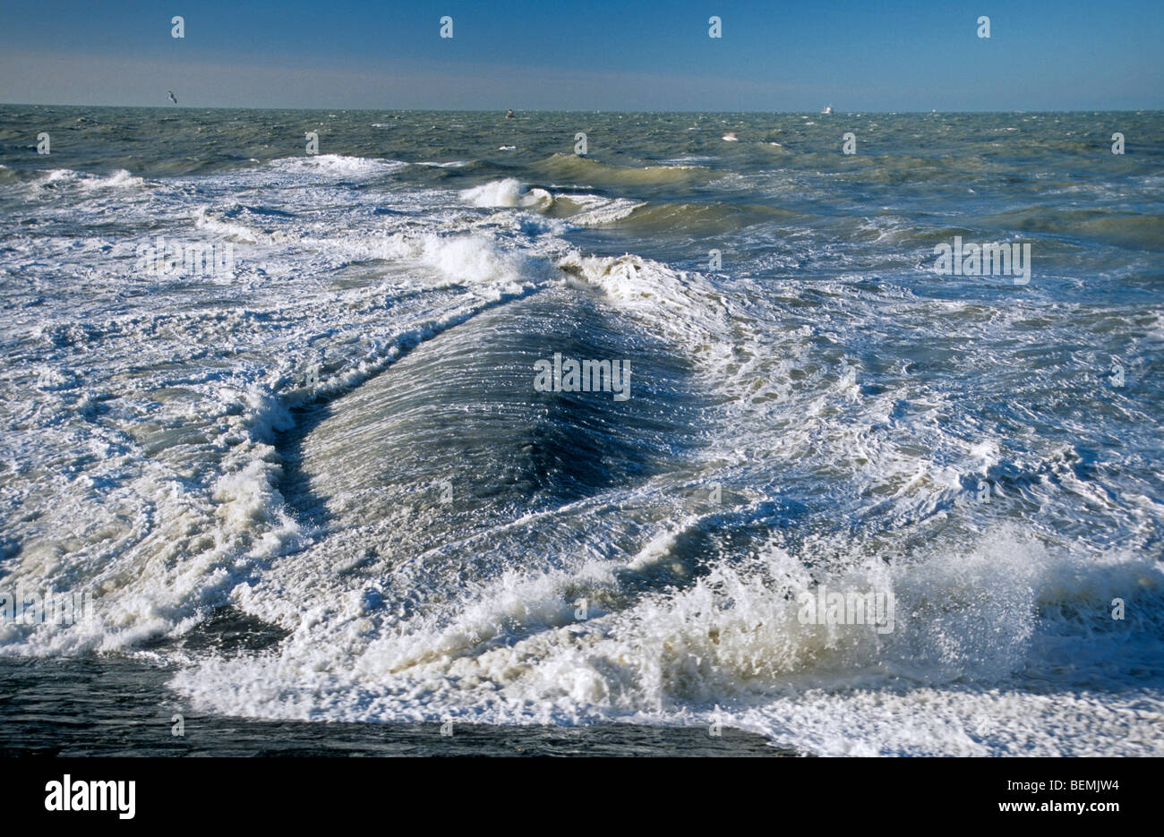 Wellen brechen über Wellenbrecher / Maulwurf / Leiste / Buhne am Strand entlang der Nordseeküste Stockfoto