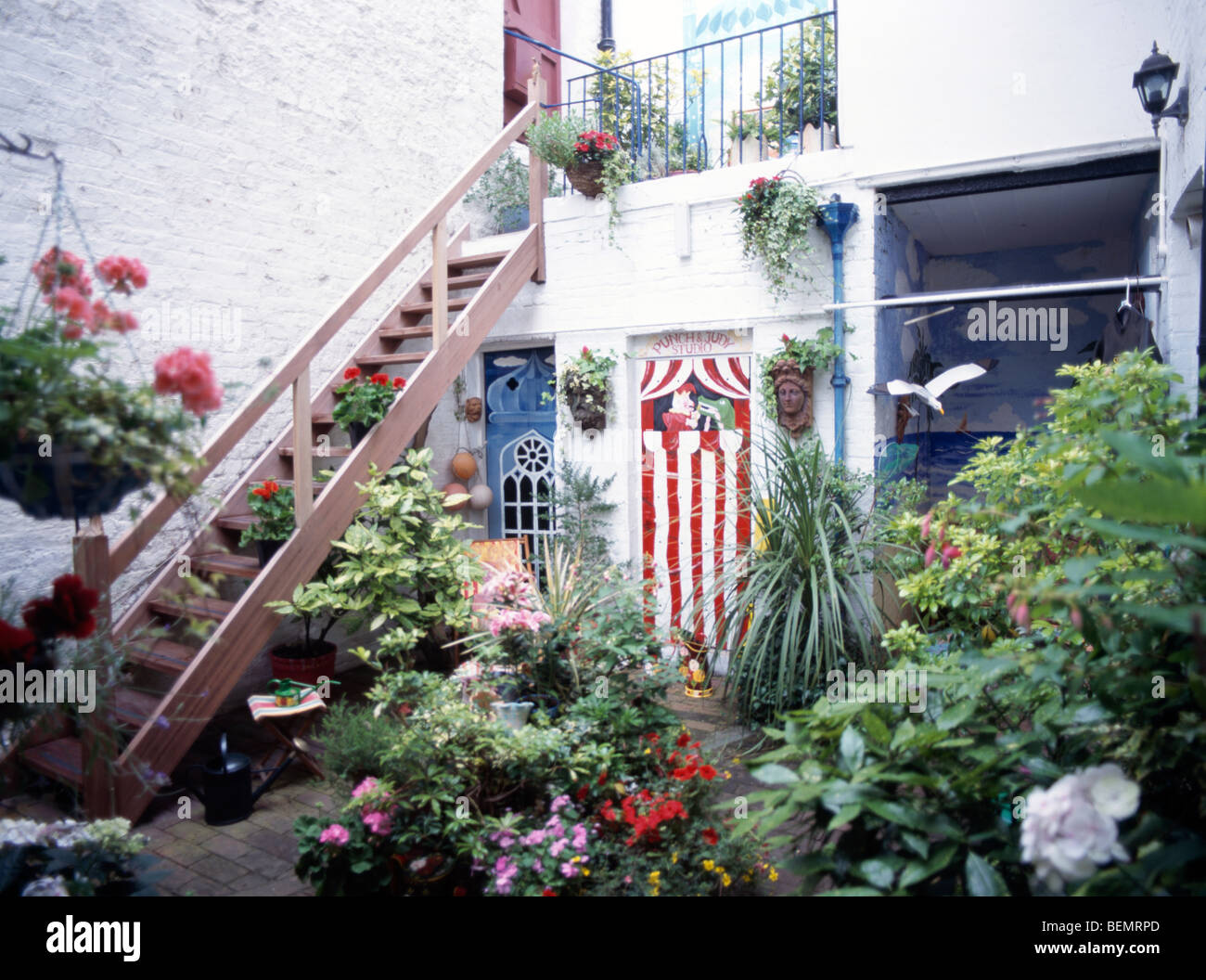Blhende Pflanzen und ppigen grnen Struchern in Tpfen im Keller Garten  mit rosa auen Treppe und gemalten Wandbild auf Wand Stockfotografie - Alamy
