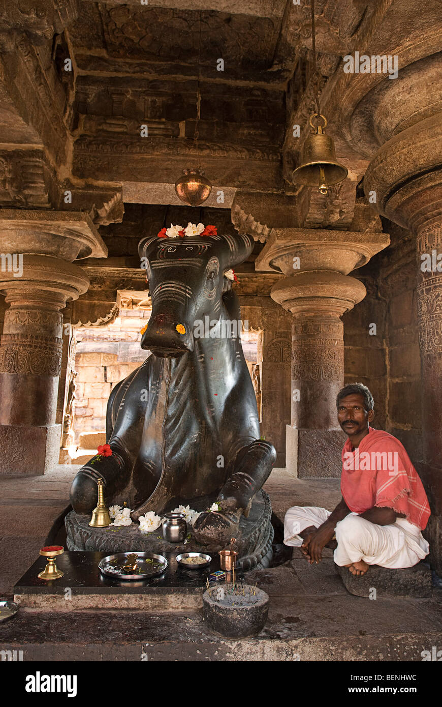 Mann sitzt neben einem Monolith Nandi-Statue in Nandi Mandapa Pattadakal Karnataka Indien Stockfoto
