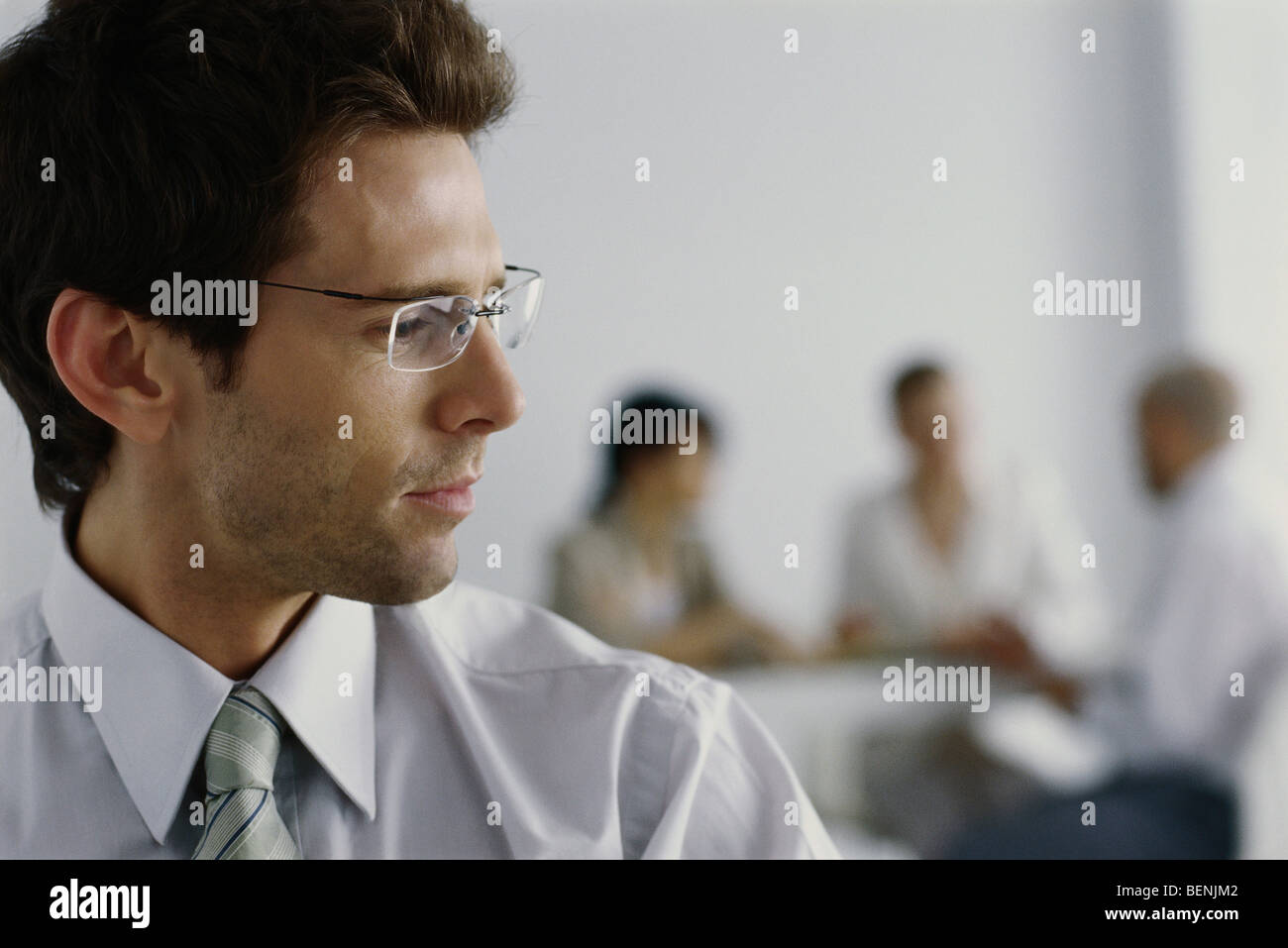 Junger Geschäftsmann in Büro, Kopf um Kollegen im Hintergrund zu hören Stockfoto