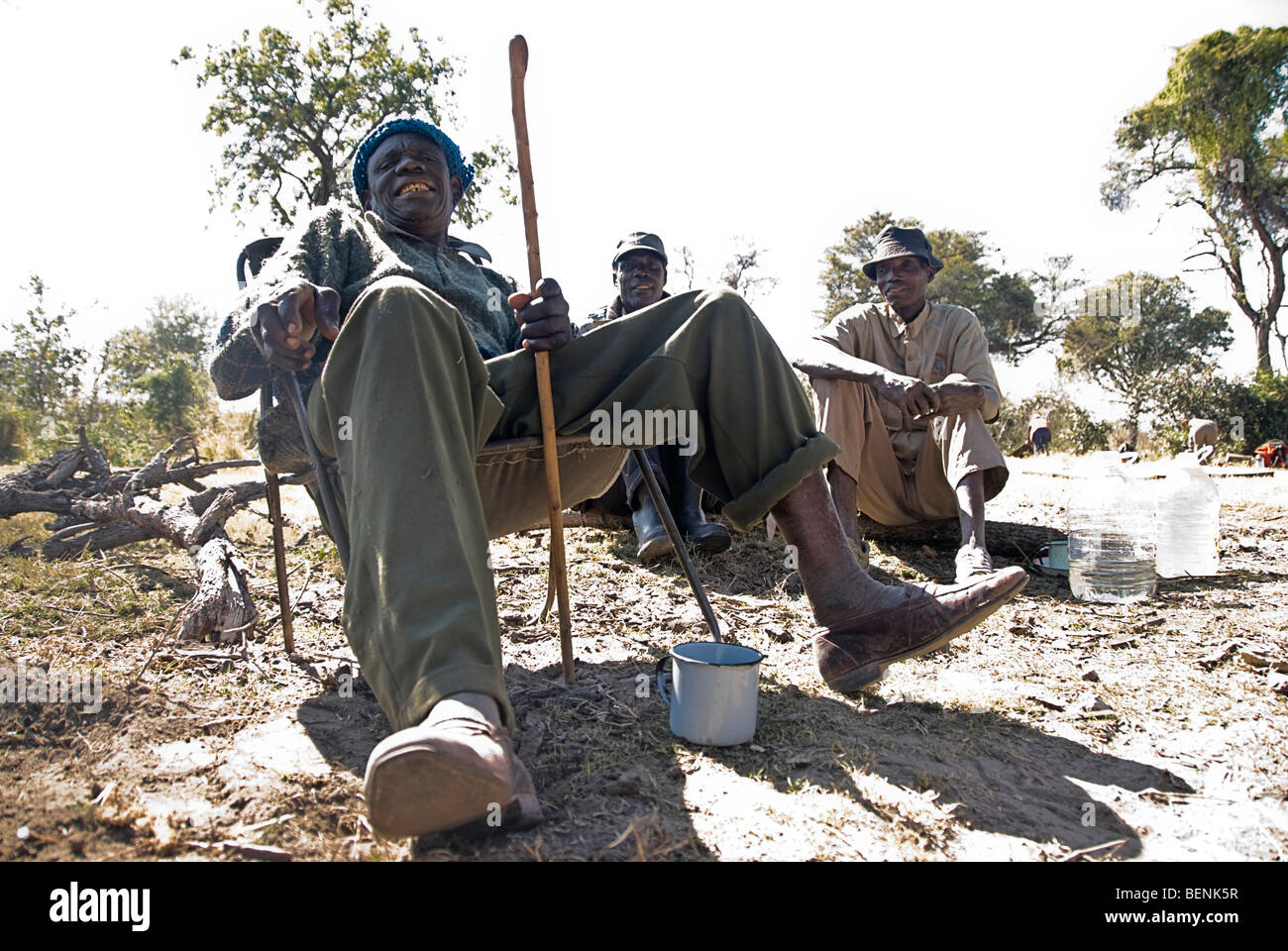 Alte Männer sitzen in der Nähe des Feuers auf ihrem Campingplatz, Okavango Delta, Botswana, Afrika. Stockfoto
