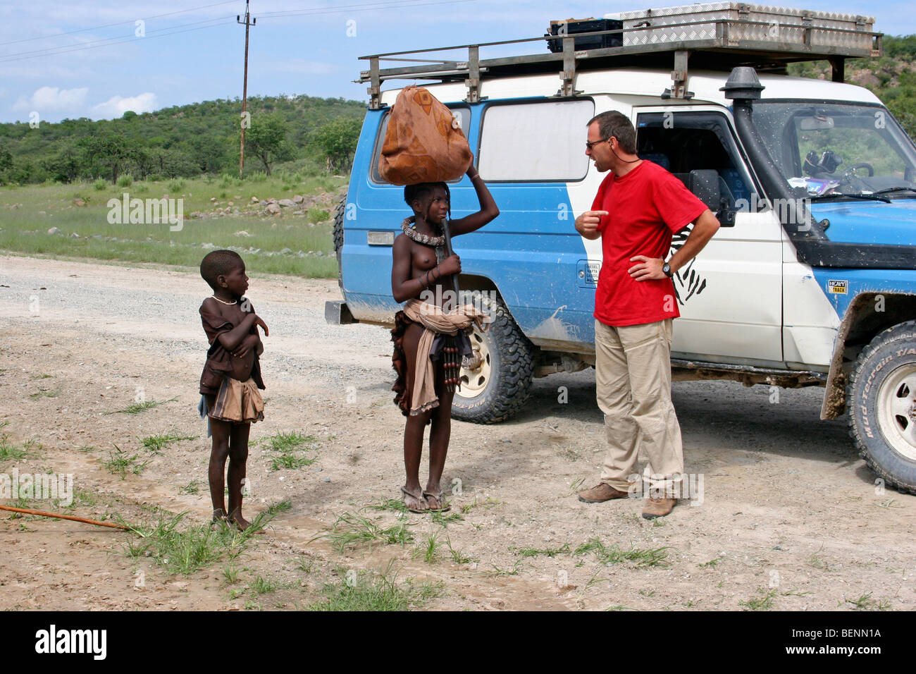 Touristen mit Allrad-Fahrzeug trifft Kinder der Himba Stamm, Kaokoland, Namibia, Südafrika Stockfoto