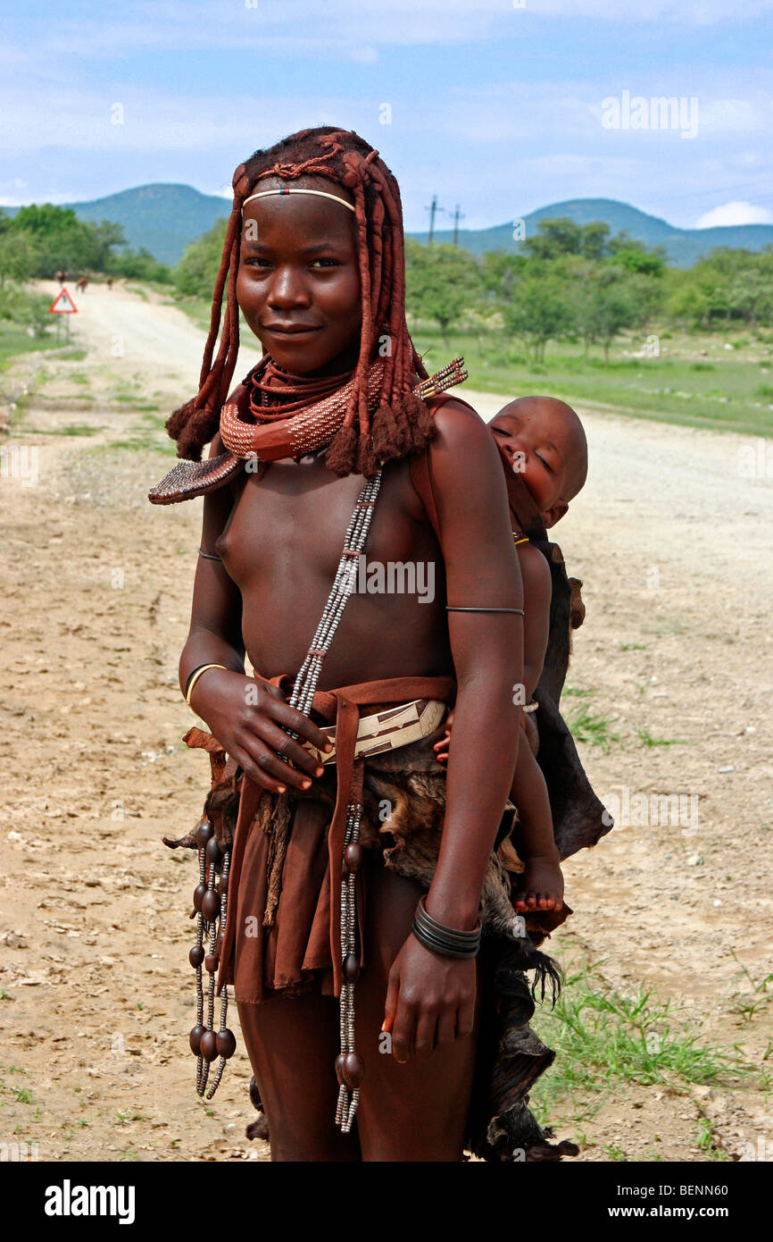 Himba-Frau mit Kind auf dem Rücken, Kaokoland / Kaokoveld, Kunene-Region, nördlichen Namibia, Südafrika Stockfoto