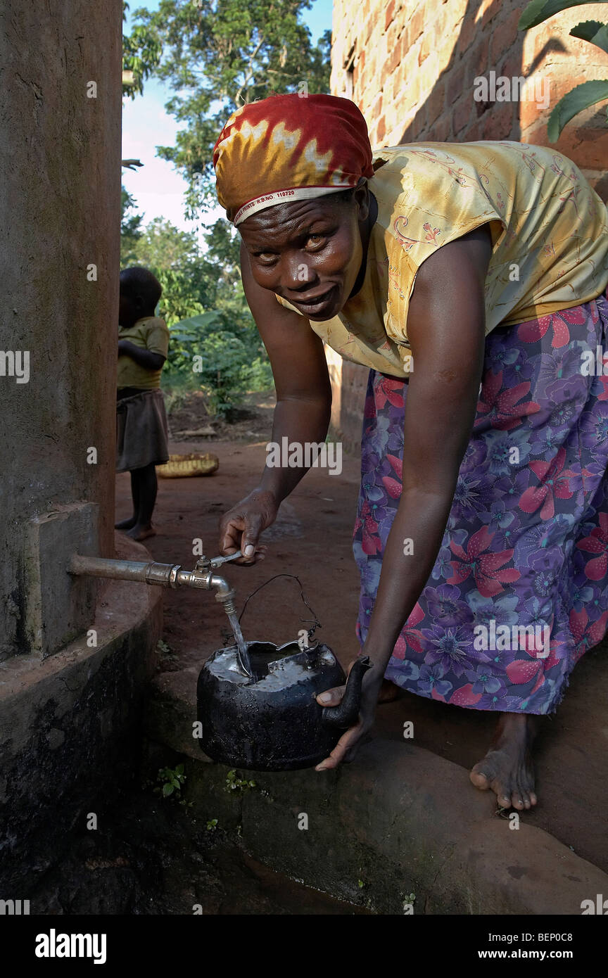 UGANDA im Hause des Najjemba Teopista, Kasaayi Dorf, Kayunga Bezirk. Teopista unter Wasser von Regentank. Stockfoto