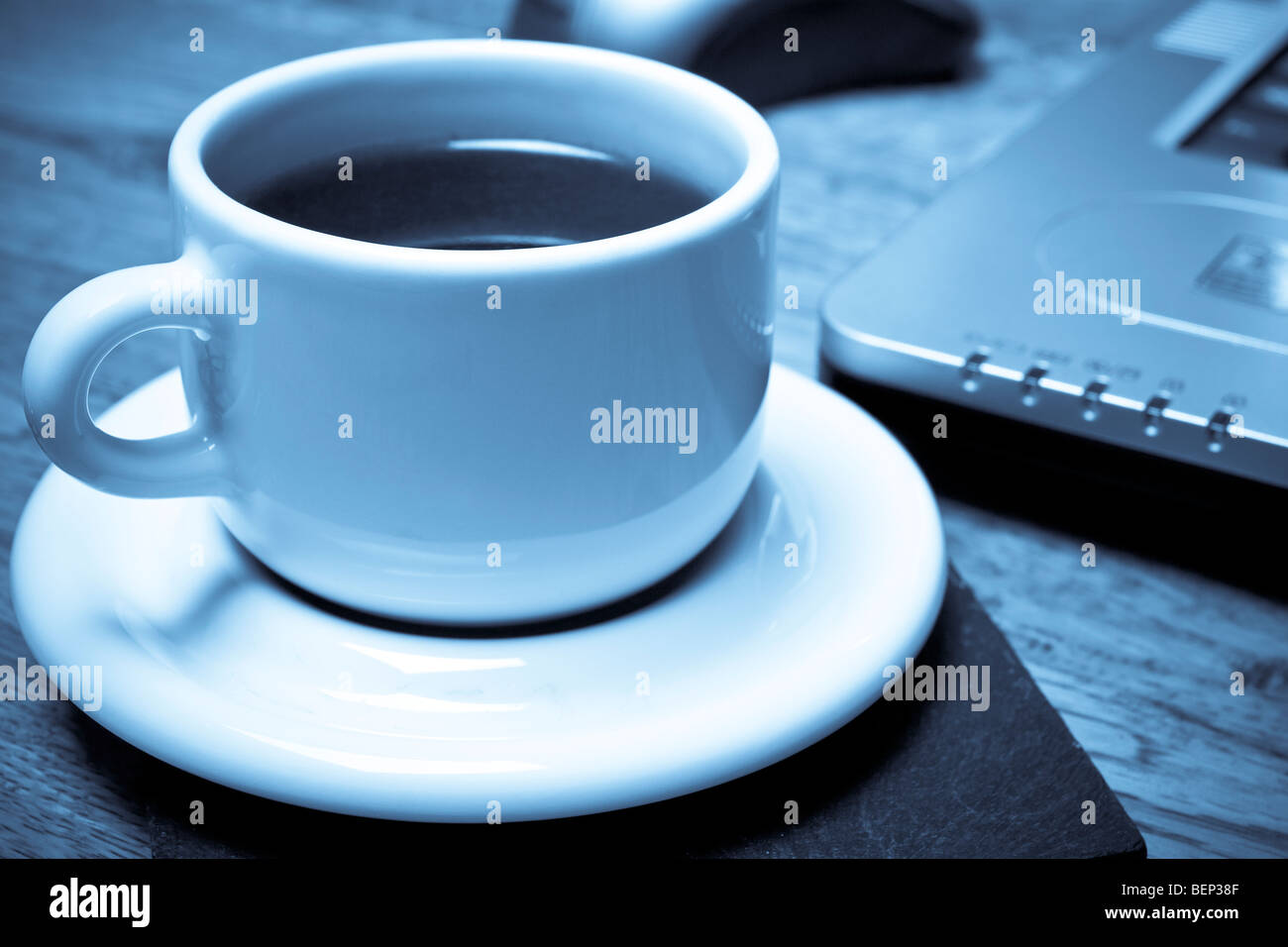 Monochromen Blauton Bild der Espresso Kaffee Tasse und Notebook-Computer auf Couchtisch. Heimarbeit-Konzept. Stockfoto