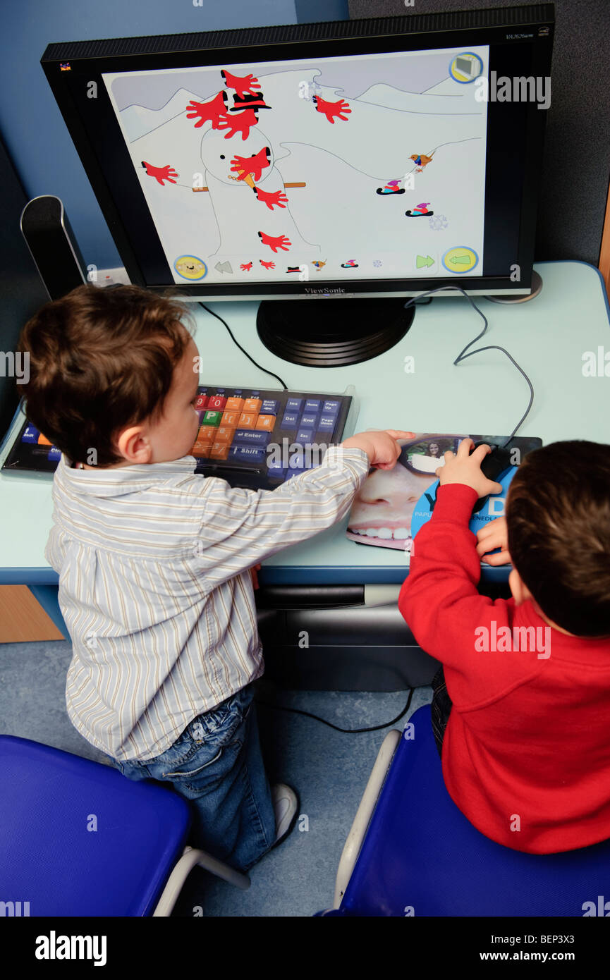 zwei junge Kinder Kleinkinder mit Hilfe eines Computers in einer walisischen Pre School Gärtnerei, Wales UK Stockfoto