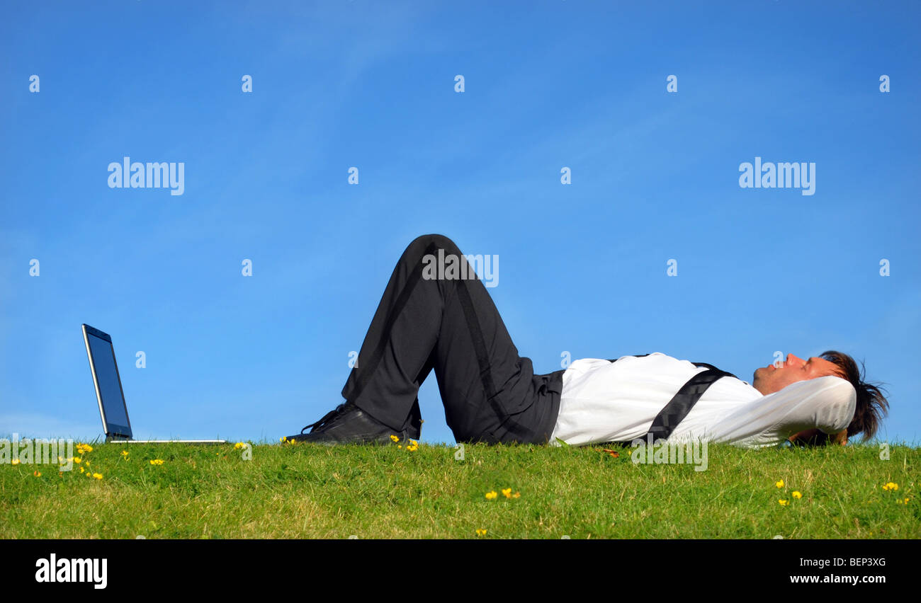 Geschäftsmann hinlegen auf Rasen und Ruhe vor seinem laptop Stockfoto
