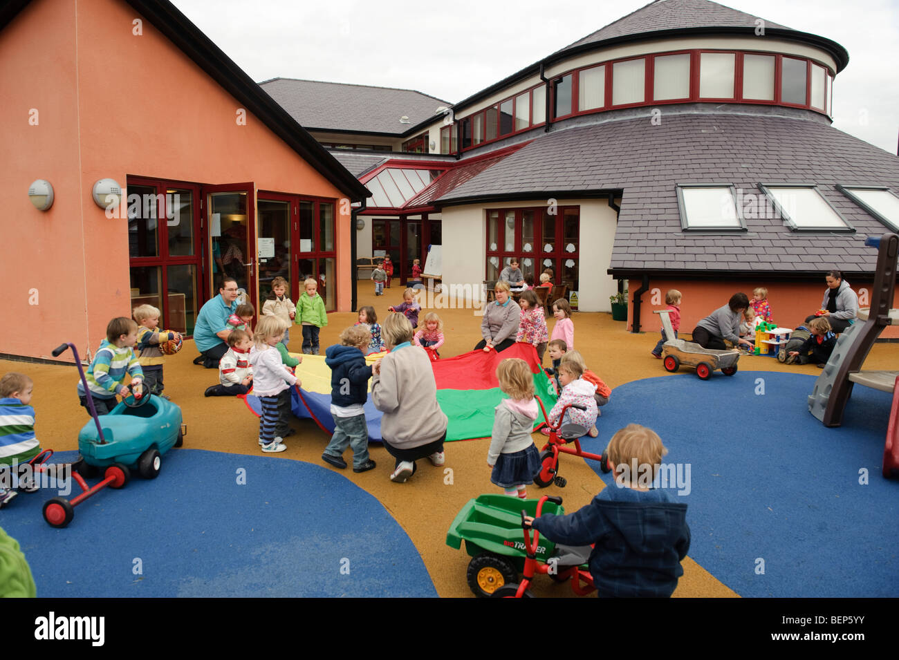 kleine Kinder spielen im Freien in einem Pre-Schule-Kindergarten-Kinderkrippe oder Kindergarten Wales UK Stockfoto