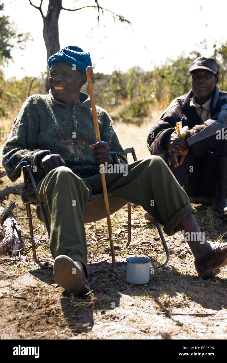 Alte Männer sitzen in der Nähe des Feuers auf ihrem Campingplatz, Okavango Delta, Botswana, Afrika. Stockfoto