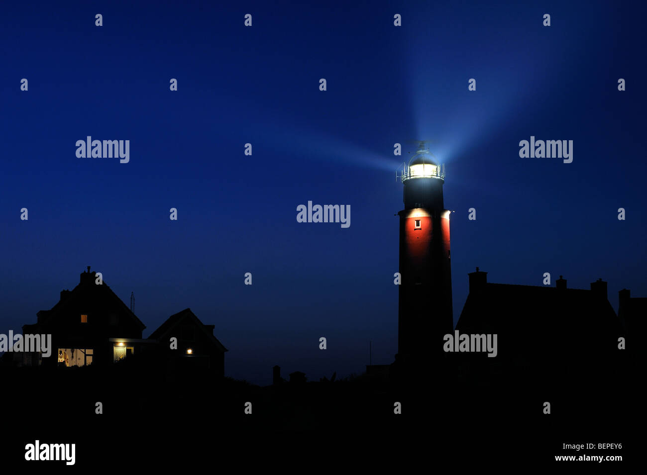 Häuser und Lichtstrahlen von Laterne Cocksdorp Leuchtturm Eierland nachts, Texel, Niederlande Stockfoto