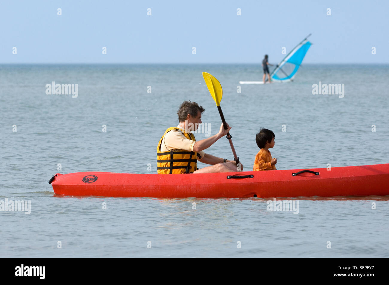 Windsurfer und Mann im Kajak mit Kind paddeln entlang der Nordseeküste Stockfoto