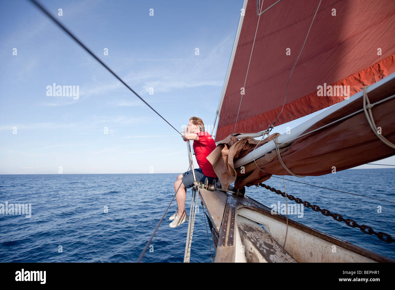 Mann sitzt am Bug eines Schiffes Stockfoto