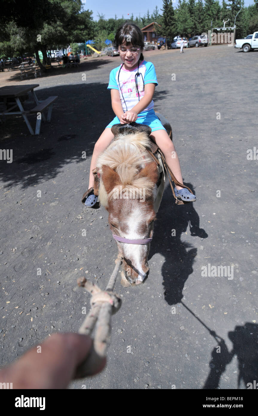 Urlaubsaktivität für Kinder ein Streichelzoo junge Mädchen von fünf auf einem pony Stockfoto