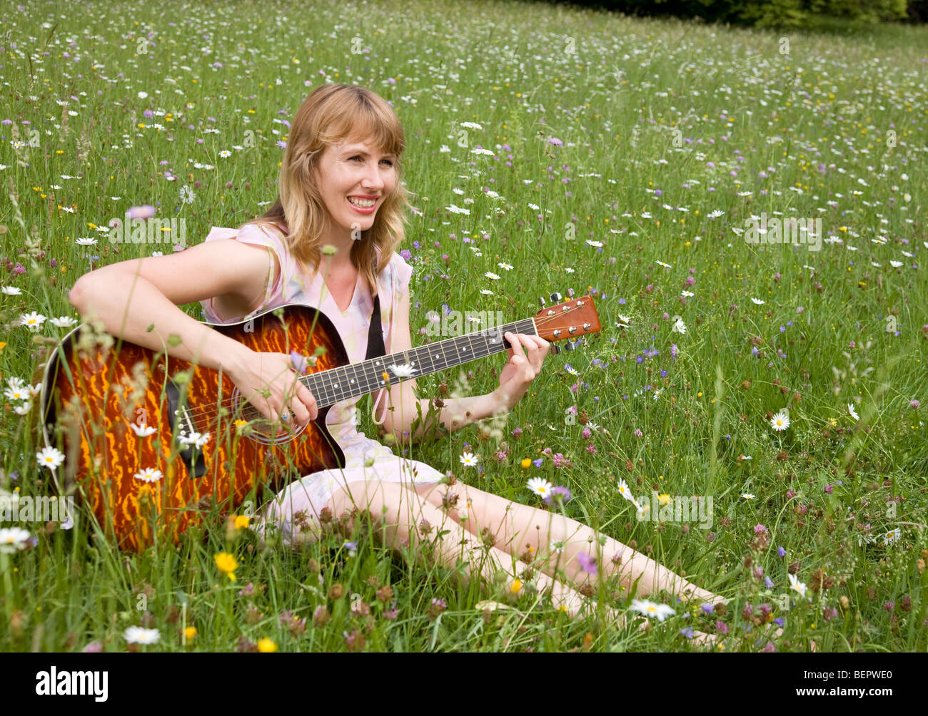 Frau spielt Gitarre in der Wiese Stockfoto