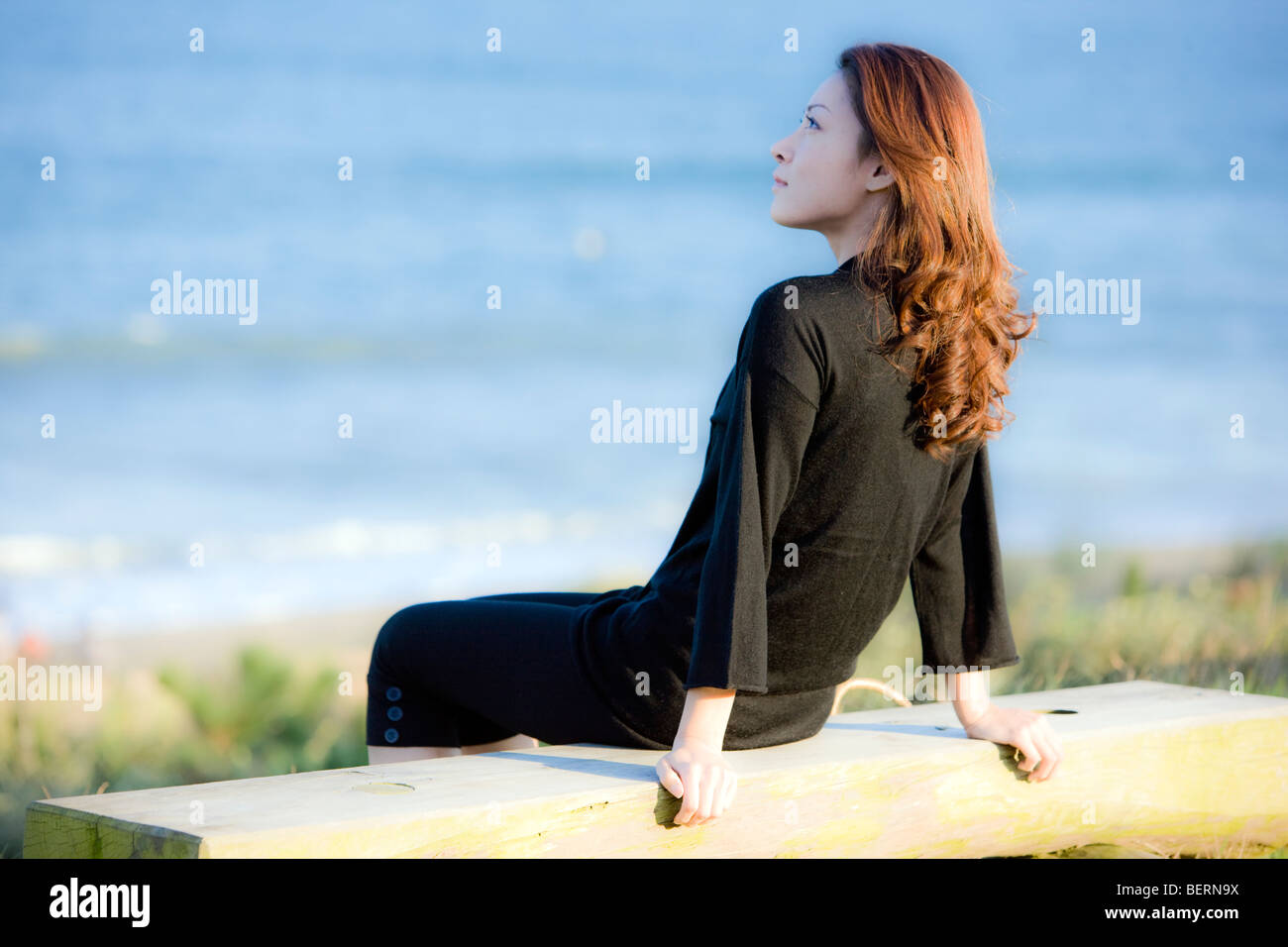 Junge Frau sitzt am Strand, weg schauen Stockfoto