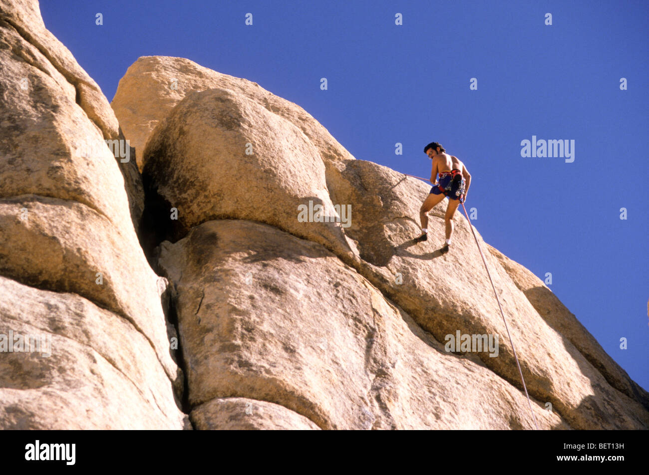 Höhepunkt Ziel Ziel Arbeit Aufwand Kunststück Nervenkitzel Gefahr Bedrohung zu überwinden bis sicher Sicherheit Sonne glühen Himmelblau klar Abseilen Stockfoto