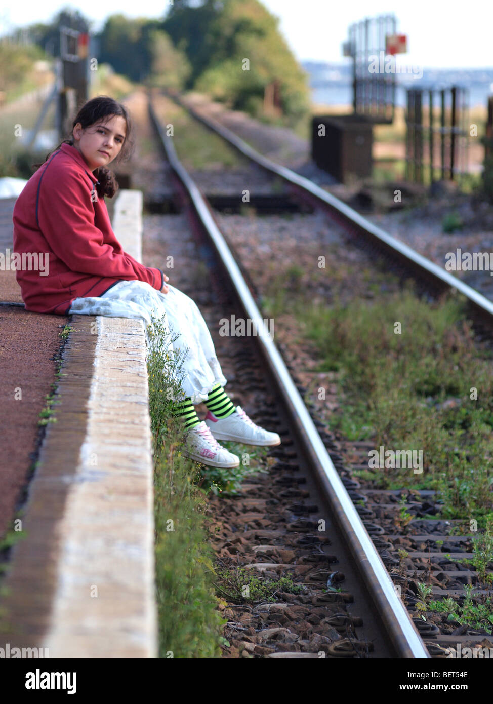 Junges Mädchen saß auf dem Rand der Bahnsteig der Zug wartete. Stockfoto