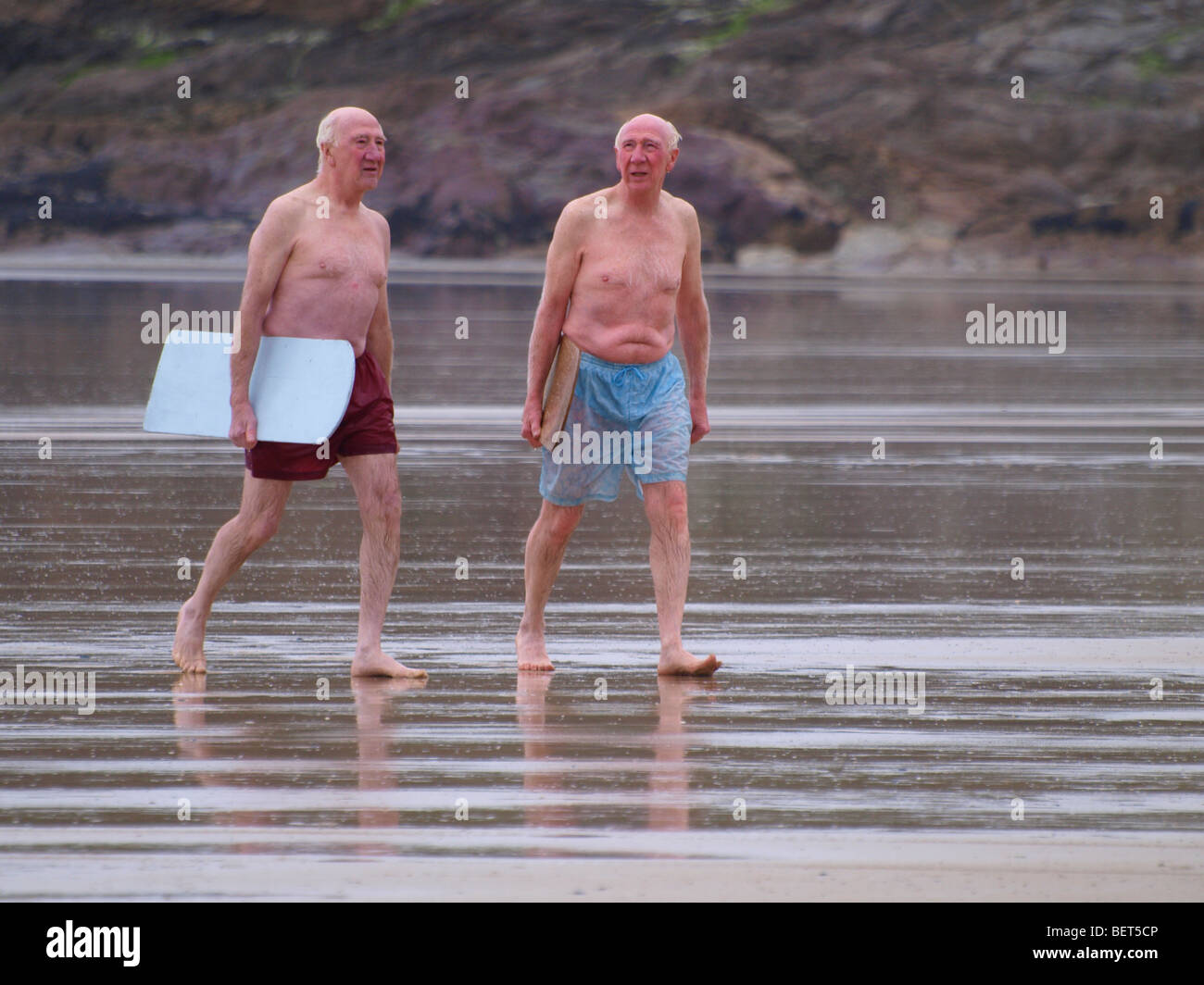Zwei alte Männer mit Bellyboards, zu Fuß bis zum Strand nach dem Schwimmen im Meer, Devon
