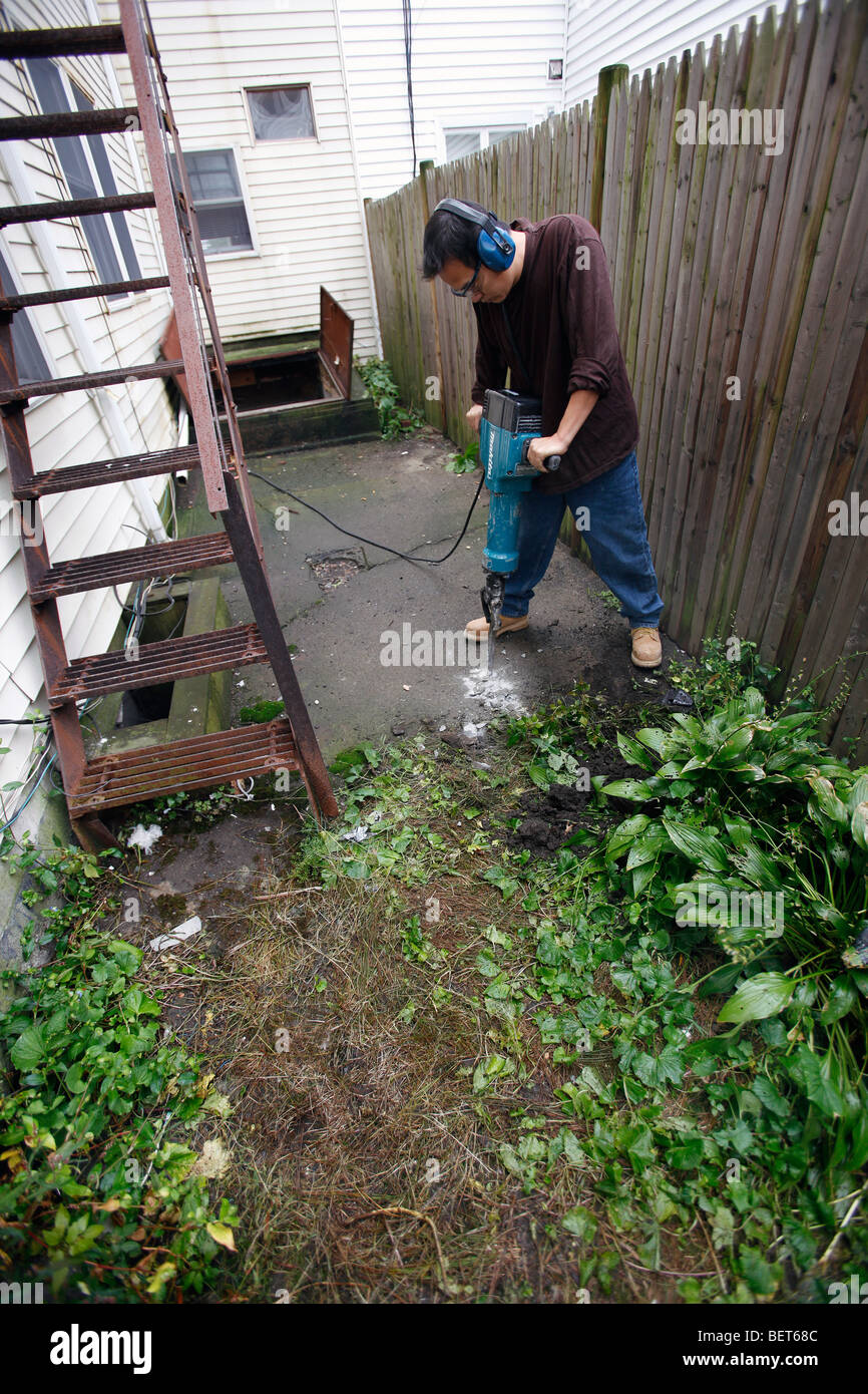 Der Mensch nutzt eine elektrische Presslufthammer auf Zement Stockfoto