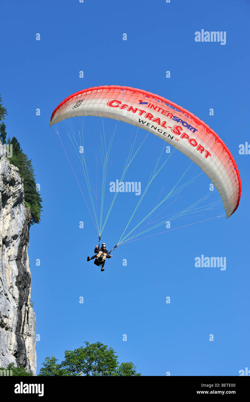 Tandem-Gleitschirm mit Pilot und Passagier fliegen entlang der Felswand in den Schweizer Alpen, Schweiz Stockfoto