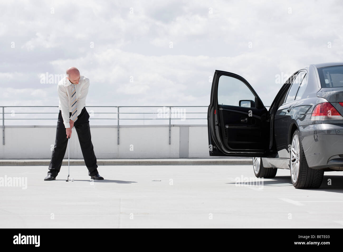 Man spielt Golf in der Nähe von Auto Stockfoto