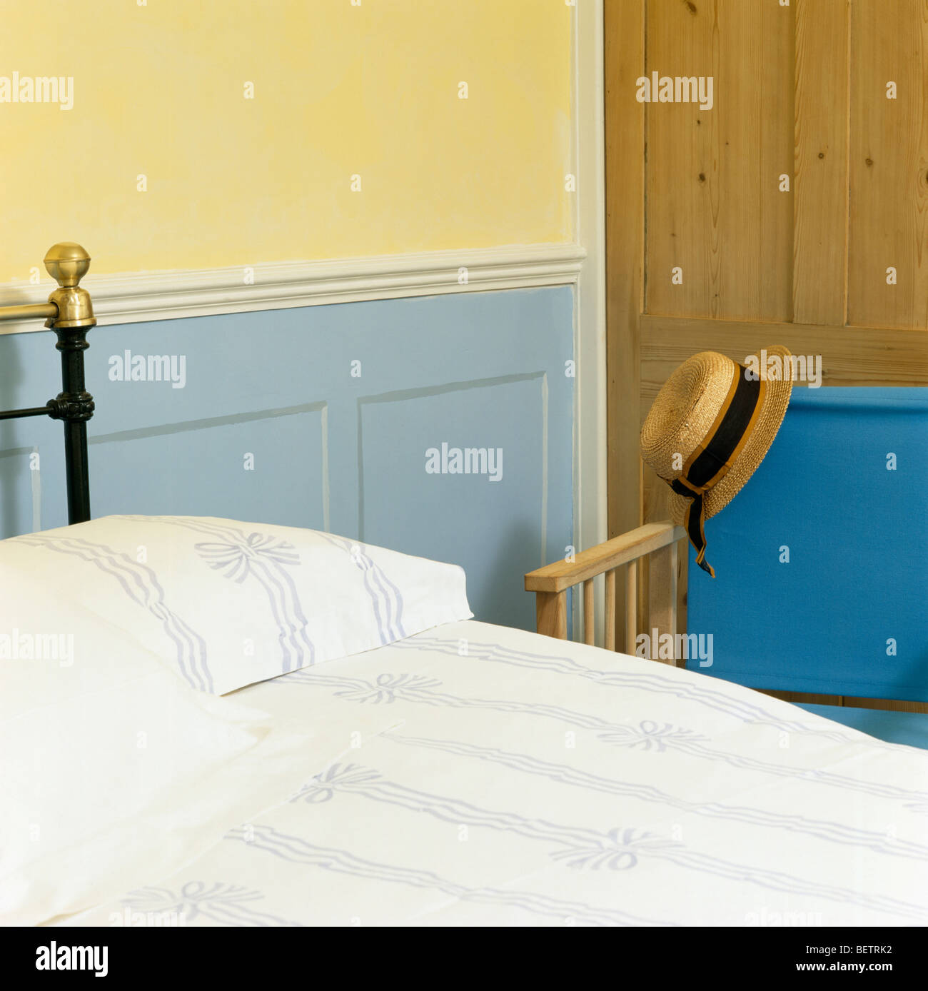 Blaue Dado Verkleidung an Wand neben Bett mit blauen + weiße Band-gemusterte Bettwäsche Stockfoto