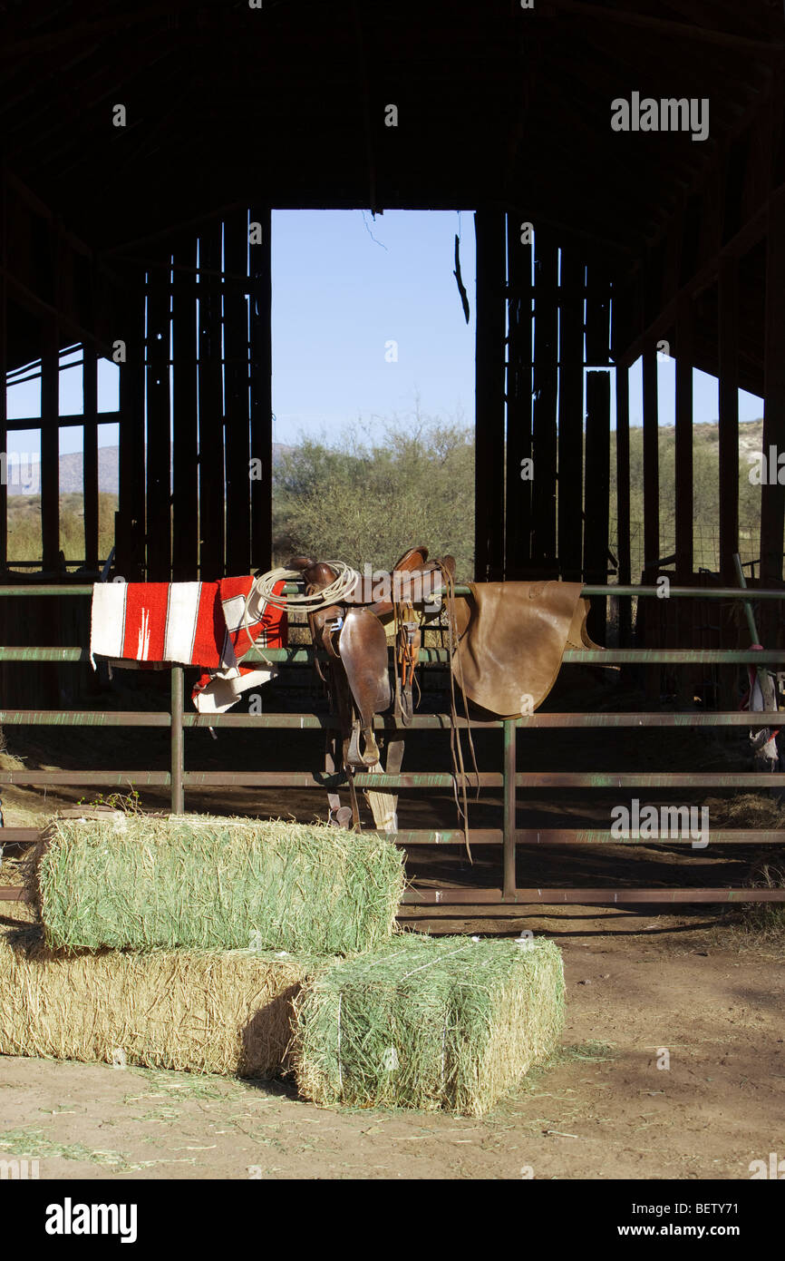 Pferdesattel, Decke, Lasso und Chaps sind bereit für den Einsatz in einer Scheune. Stockfoto