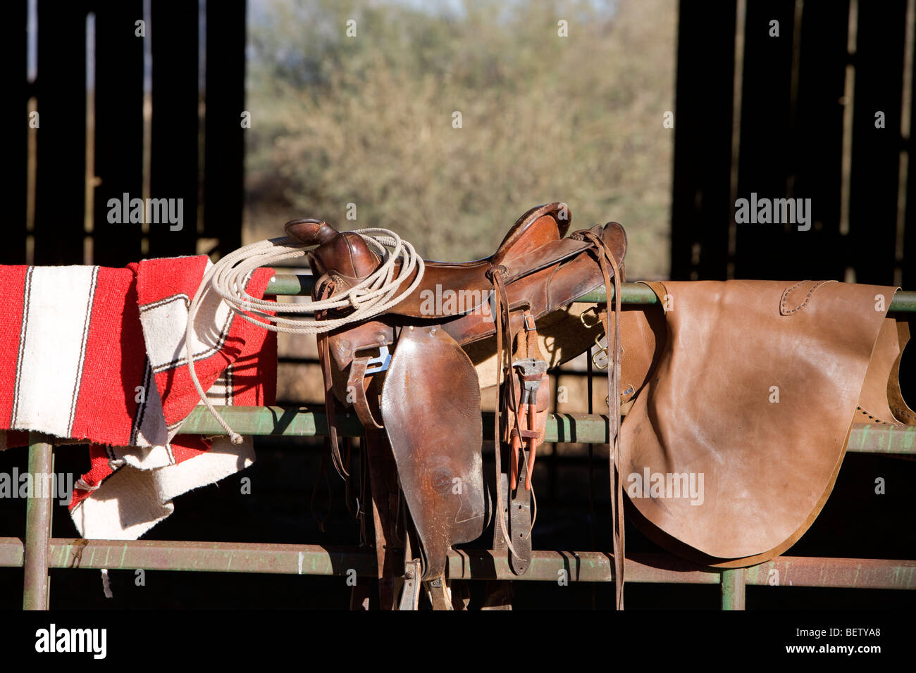 Pferdesattel, Decke, Lasso und Chaps sind bereit für den Einsatz in einer Scheune. Stockfoto