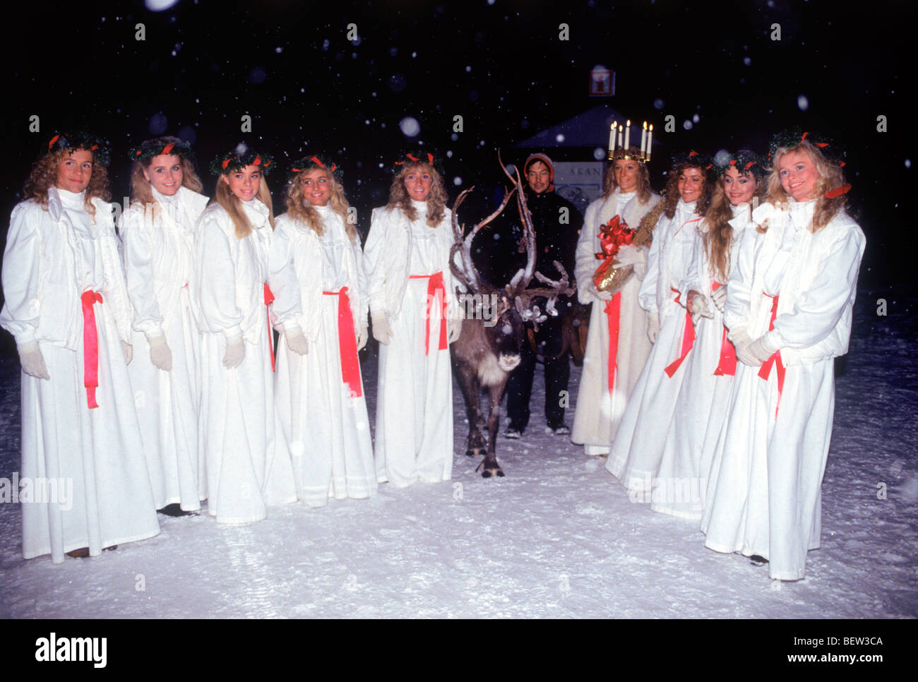 Miss Lucia Queen und Prinzessinnen im Park Skansen in Stockholm am 13. Dezember mit Rentier und Schnee fällt Stockfoto