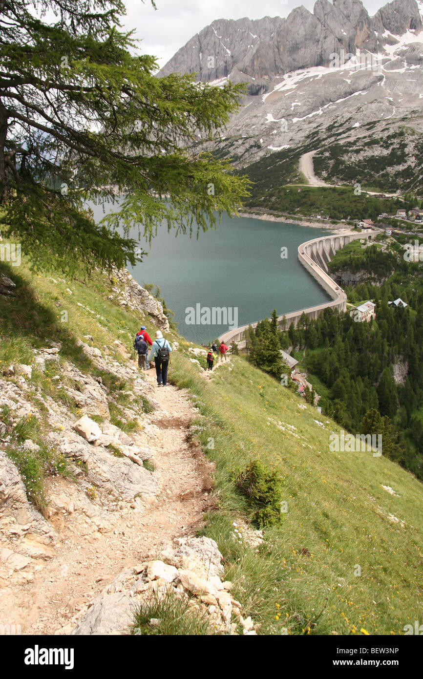Wanderer auf dem Weg zu den Lago Fedaia dam Wand unterhalb der Marmolada, Dolomiten im Sommer Stockfoto