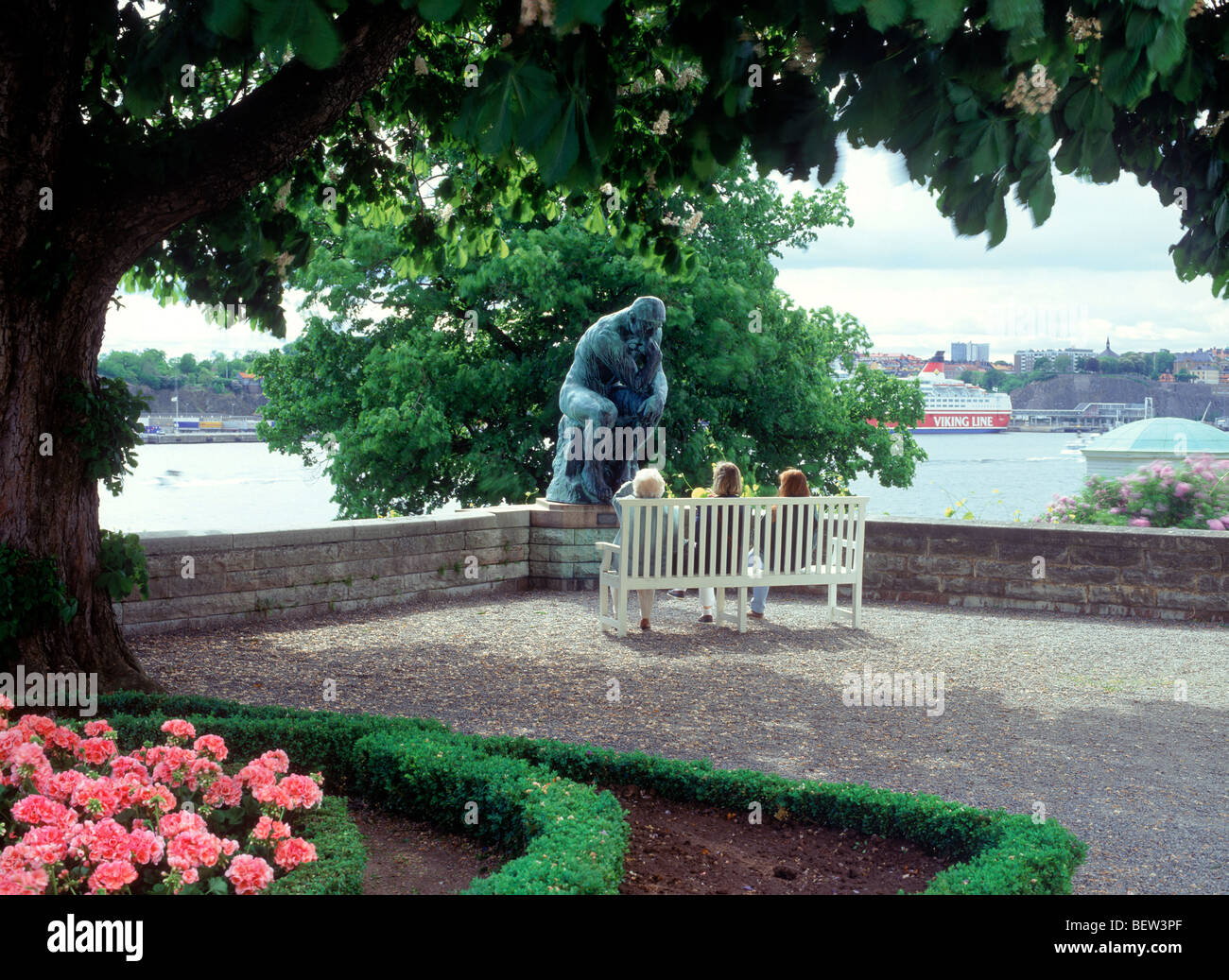 Menschen sitzen auf der Parkbank neben Auguste Rodins berühmte Skulptur "Der Denker" in Waldemarsudde auf Sommertag in Stockholm Stockfoto