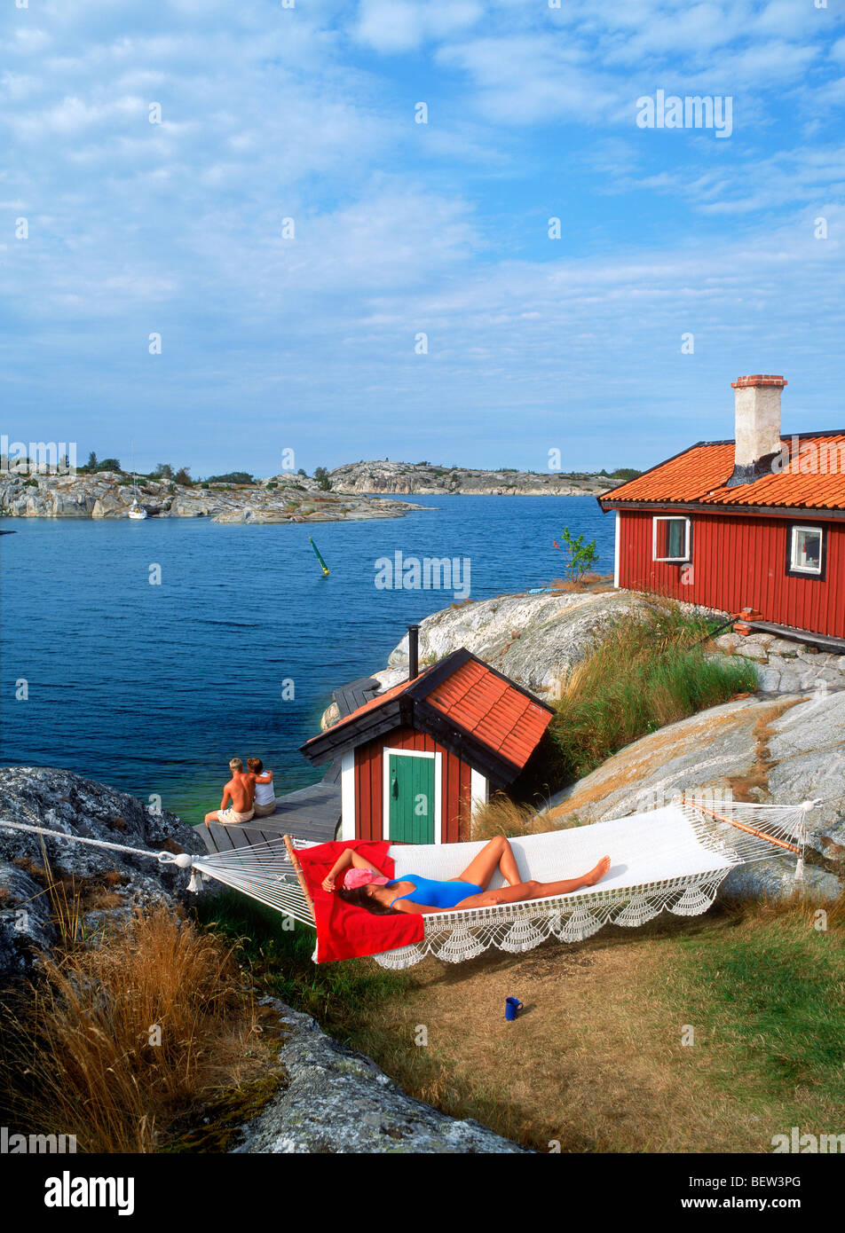 Frau in Hängematte auf Huvudskar Huvudskär Insel ruhen mit roten Sommerhaus in schwedischen Schären südlich von Stockholm Stockfoto