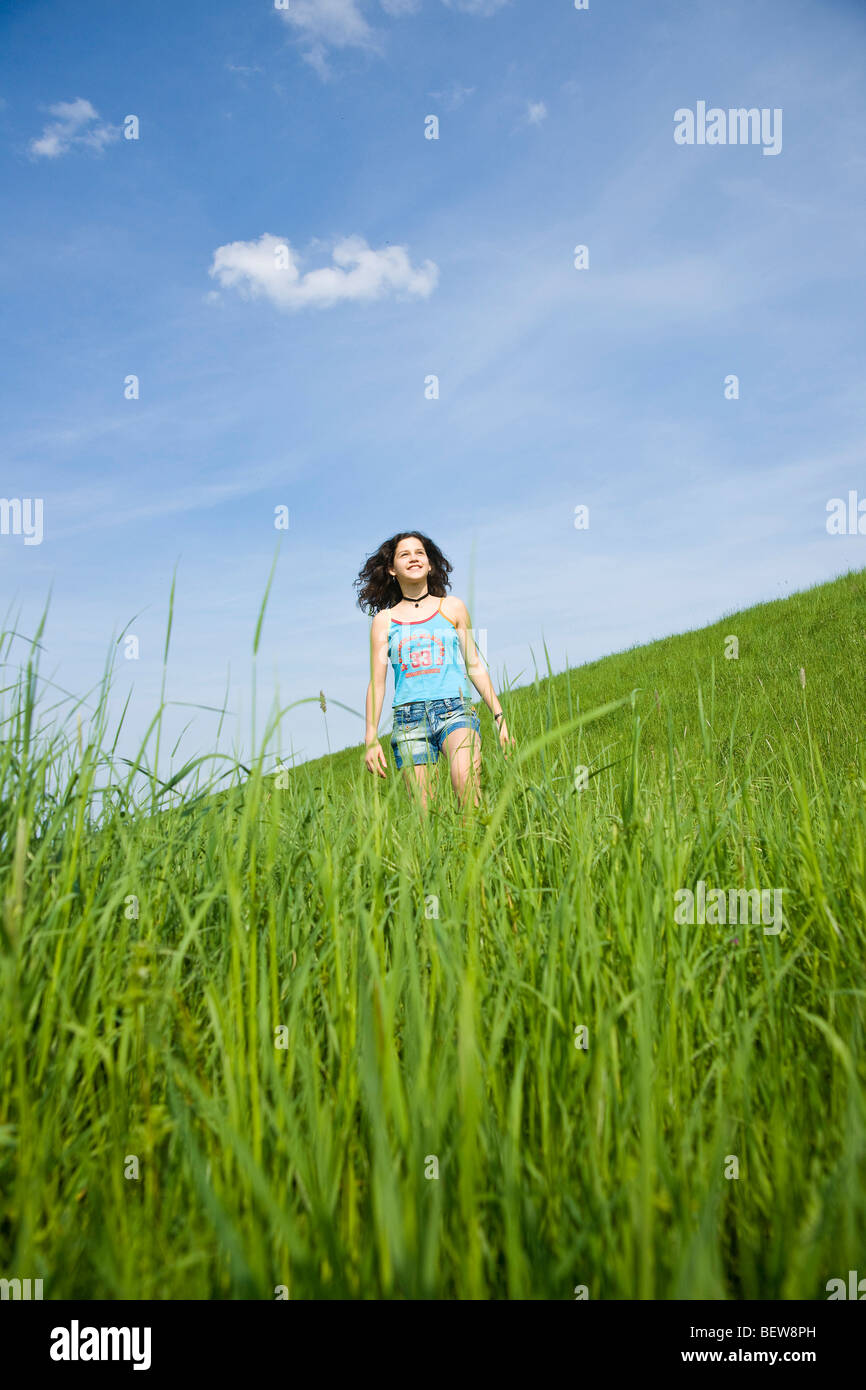 Junge Mädchen zu Fuß durch eine reiche grüne Wiese, niedrigen Winkel Ansicht Stockfoto