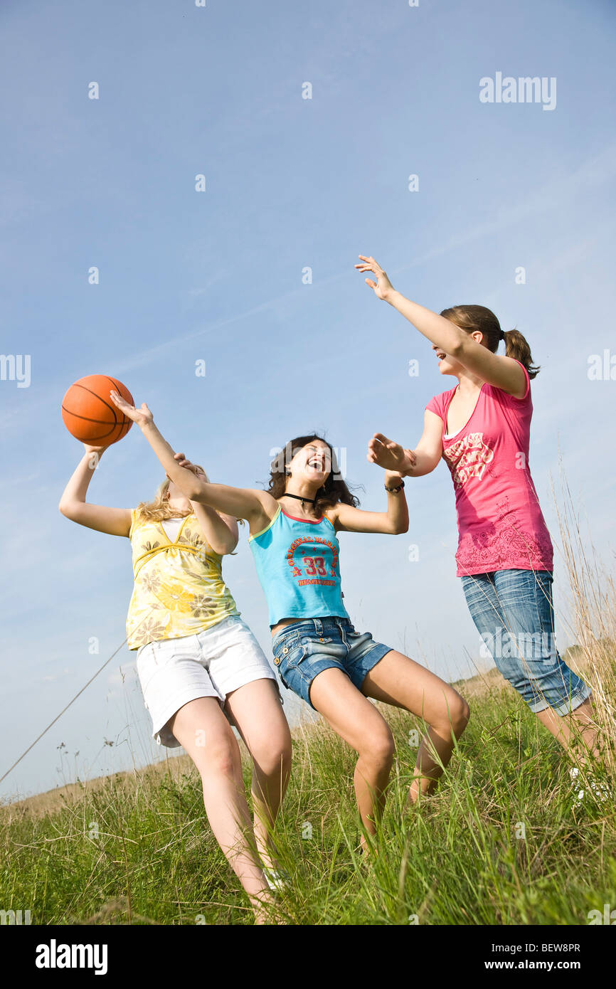 Drei junge Mädchen spielen auf einer Wiese einen Ball, niedrigen Winkel Ansicht Stockfoto