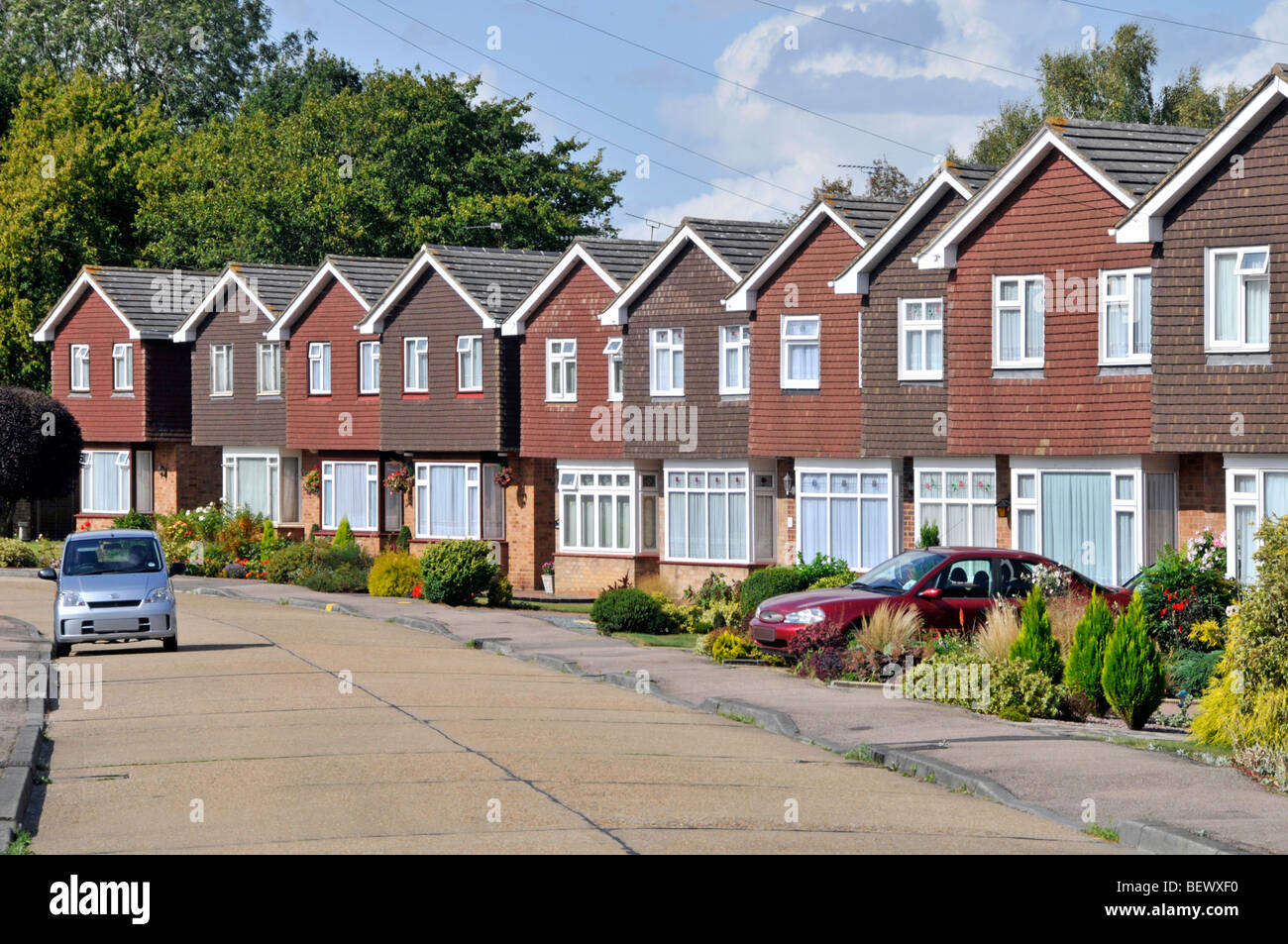 Reihe von Häusern in Wohnstraße von Immobilien-Gehäuse Grundstücksentwicklung identische Einfamilienhäuser individuelle Gärten & Auto Auffahrt England GB Stockfoto