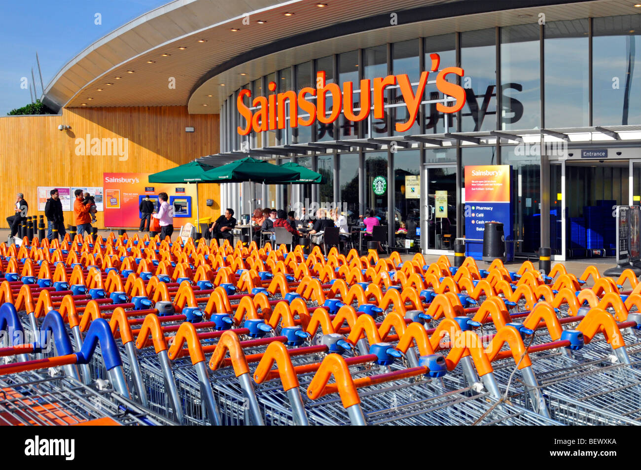 Sainsburys Supermarkt Einzelhandel Geschäftsschild & Geschäft Front Trolley Cart Park und Ladeneingang mit Starbucks Coffee Shop Greenwich London England UK Stockfoto