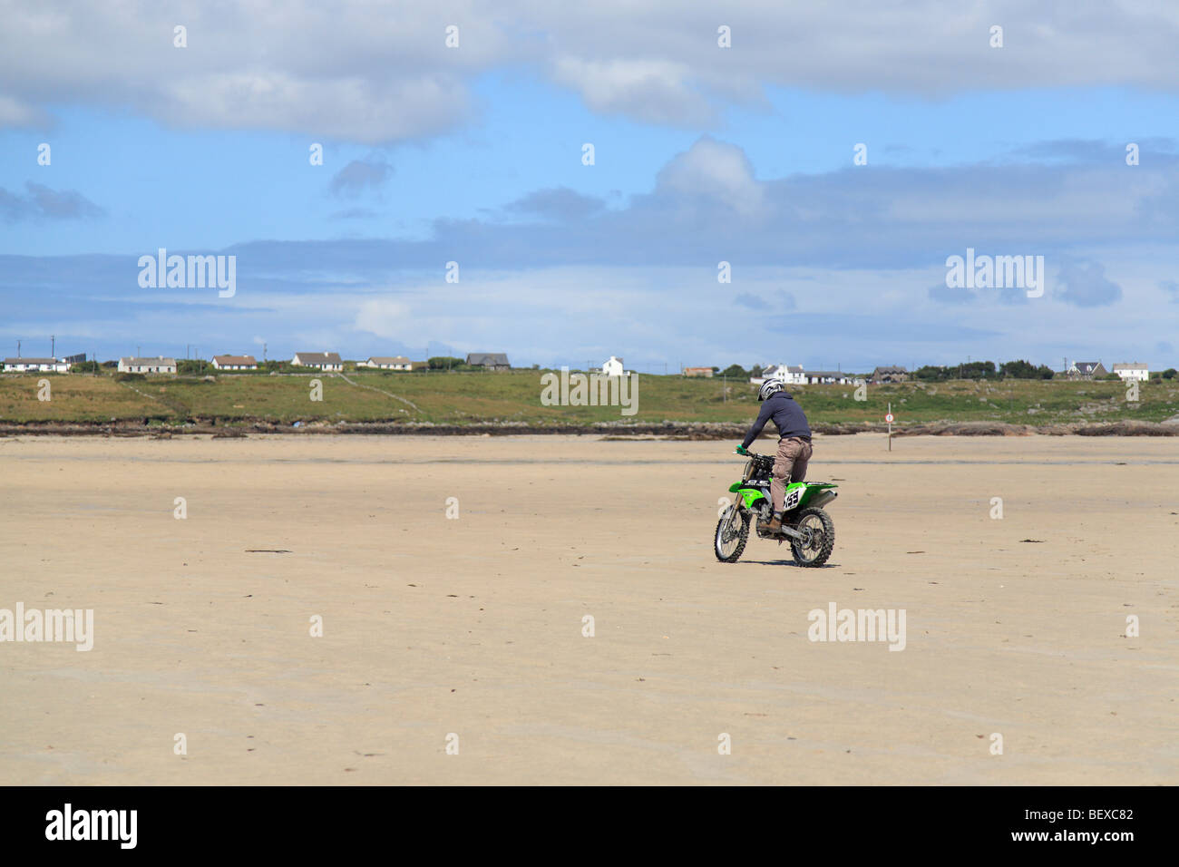 ein Kreuz Biker am Sandstrand auf Omey Insel bei Ebbe, Irland; Blick auf Claddaghduff Stockfoto