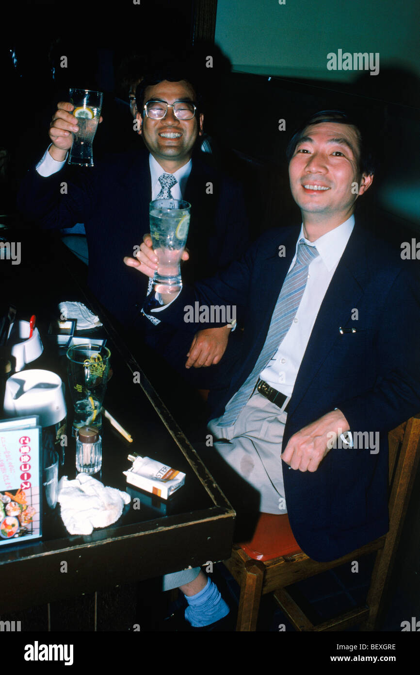 Japanische Geschäftsleute sitzen an Tischen im Restaurant Sake zu trinken Stockfoto