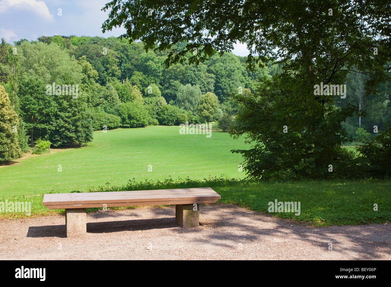 Hölzerne Parkbank mit Blick auf ein Feld und Wald in einem innerstädtischen park Stockfoto