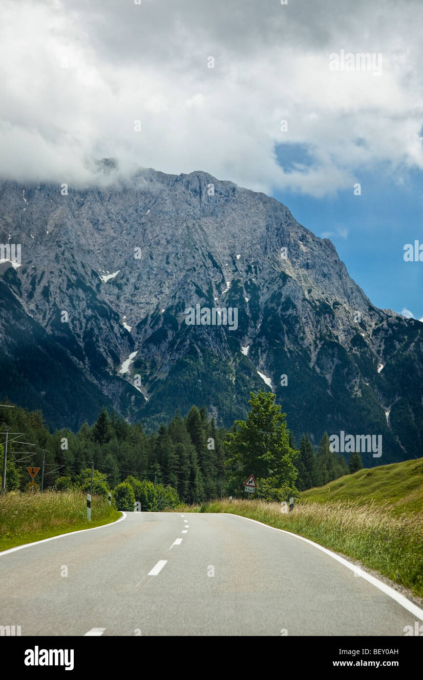 Reisen auf offener Straße durch einen Wald in Richtung Berge in Bayern, Deutschland, Europa Stockfoto