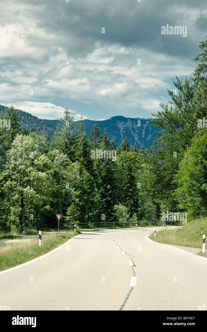 Offener Straße durch den Wald in Richtung Berge in Bayern Deutschland Europa Stockfoto