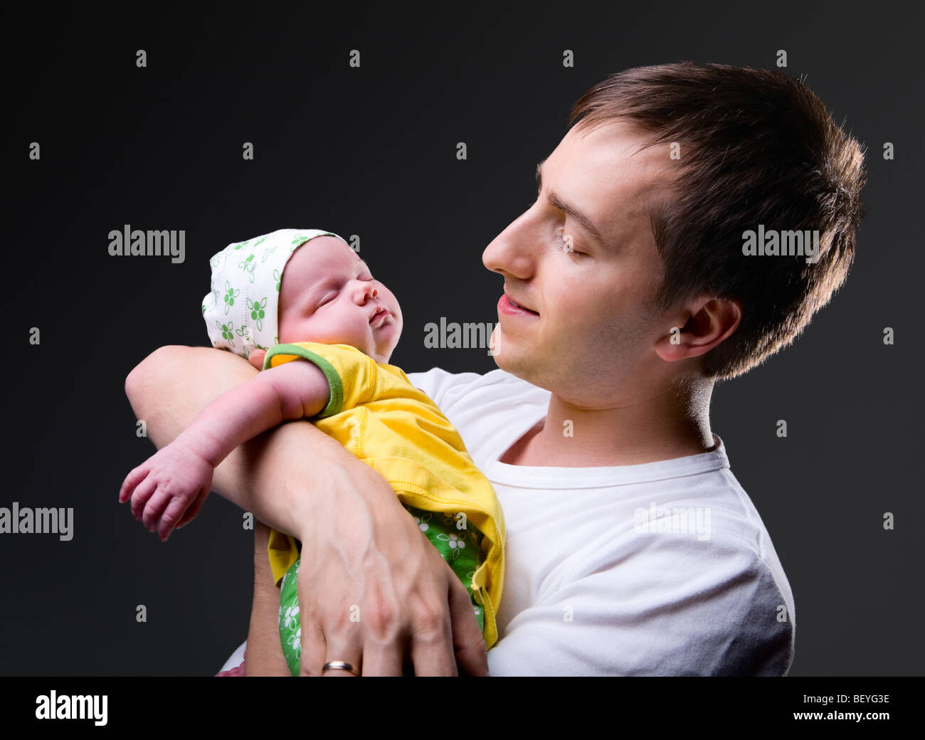 Studio Bild der glückliche junge Vater mit seiner 14 Tage alten neugeborenen Tochter auf schwarzem Hintergrund Stockfoto