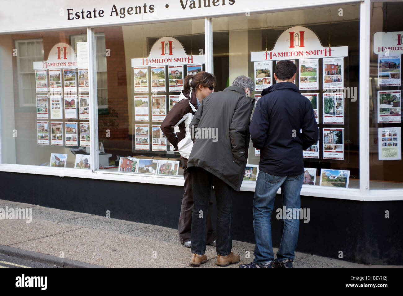 Haus Käufer suchen im Fenster der Immobilienmakler in der Marktstadt Woodbridge, Suffolk, UK. Stockfoto