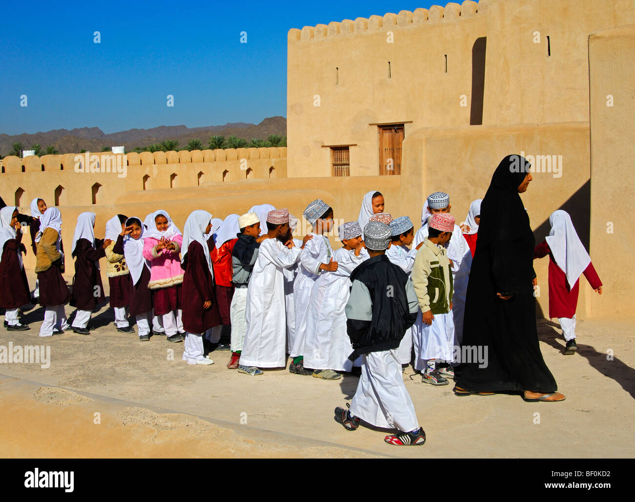 Lehrerin einer gemischten Schule Klasse von lebhaften jungen und Mädchen auf einen Ausflug in die Burg von Nizwa, Sultanat von Oman Stockfoto
