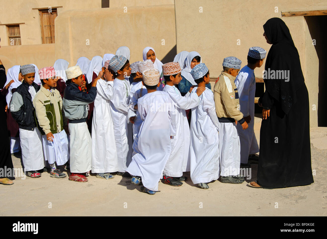 Lehrerin einer gemischten Schule Klasse von lebhaften jungen und Mädchen auf einen Ausflug in die Burg von Nizwa, Sultanat von Oman Stockfoto