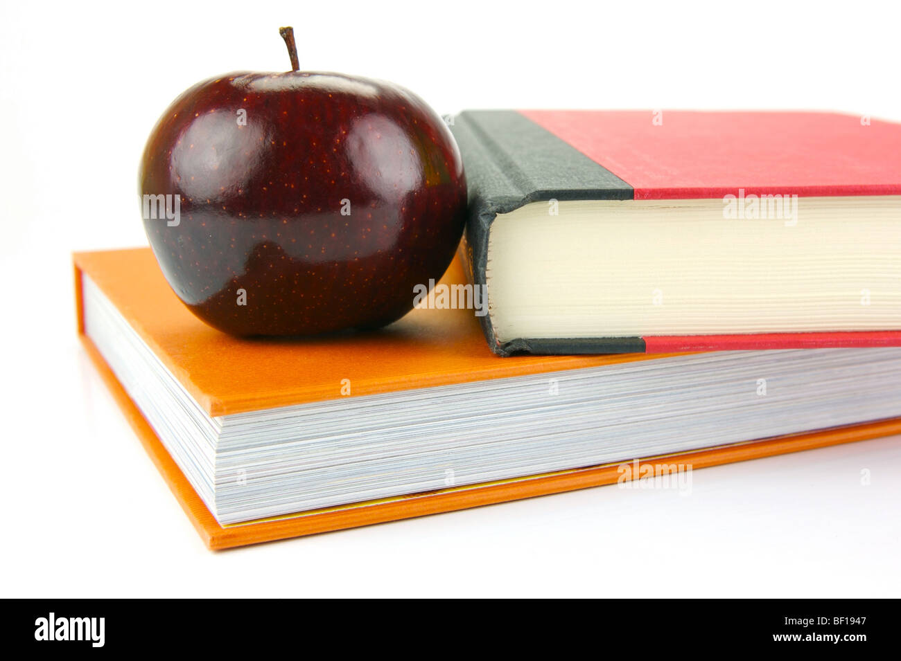 Ein roter Apfel, isoliert auf weißem Hintergrund mit Schulbüchern Stockfoto