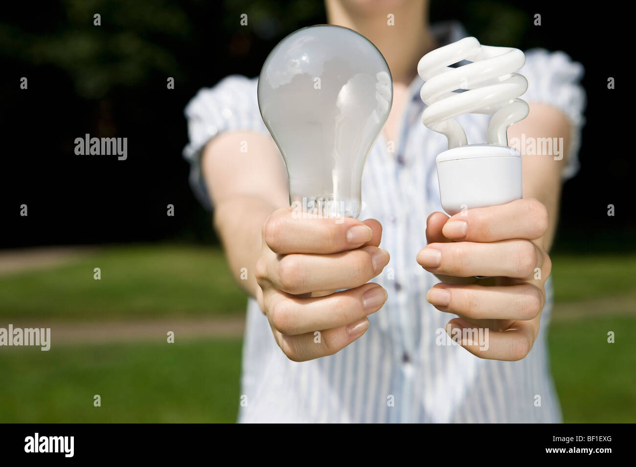 Eine junge Frau in der Hand aus einer normalen Glühlampe und einer Energiesparlampe Stockfoto