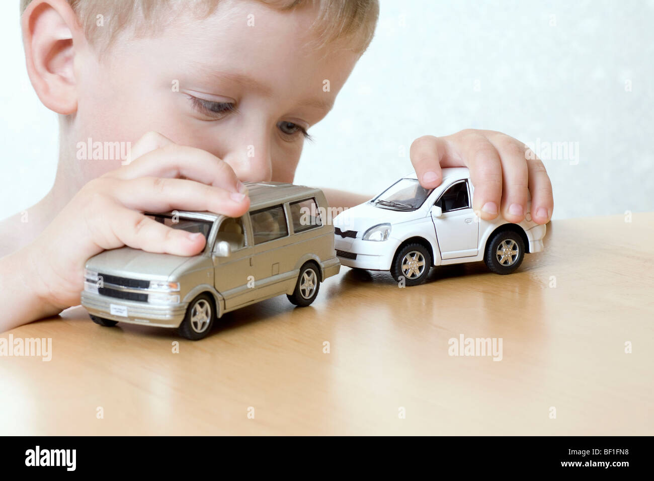Ein Junge spielt mit zwei Spielzeugautos Stockfoto
